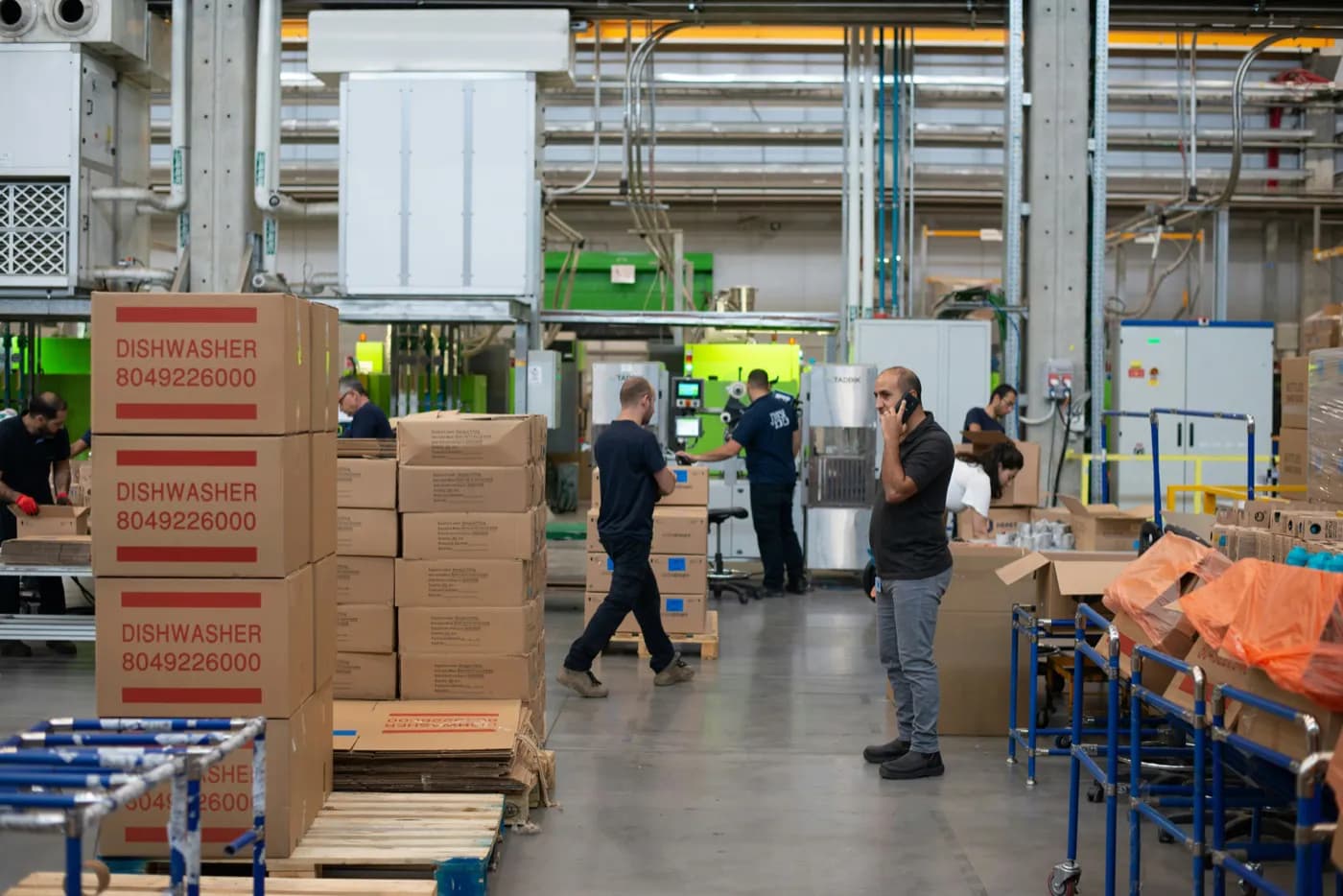 Sevkiyat alanında telefonla konuşan bir çalışan ve paketlenmeyi bekleyen koliler